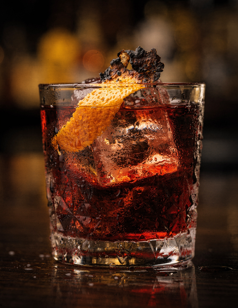 Negroni im Tumbler mit großem Eiswürfel und Orangenzeste